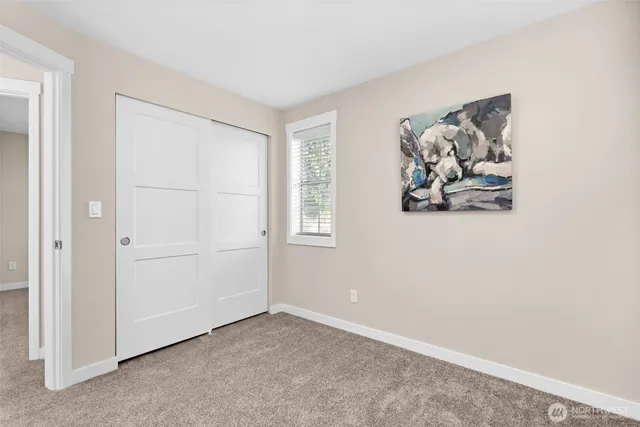 a view of an empty room with closet and a window