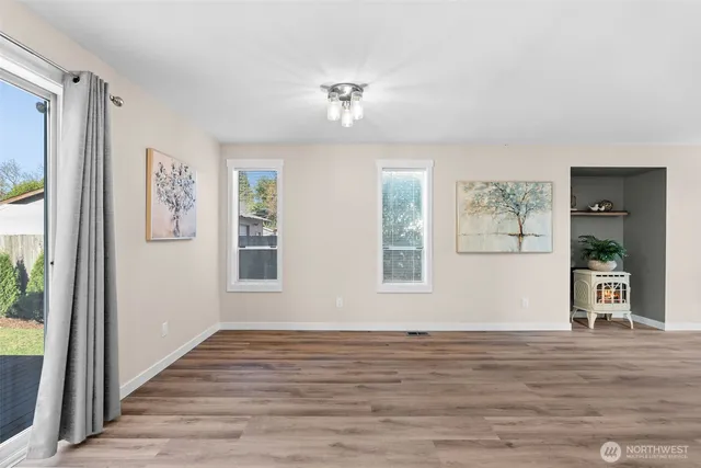 a view of an empty room with window and wooden floor