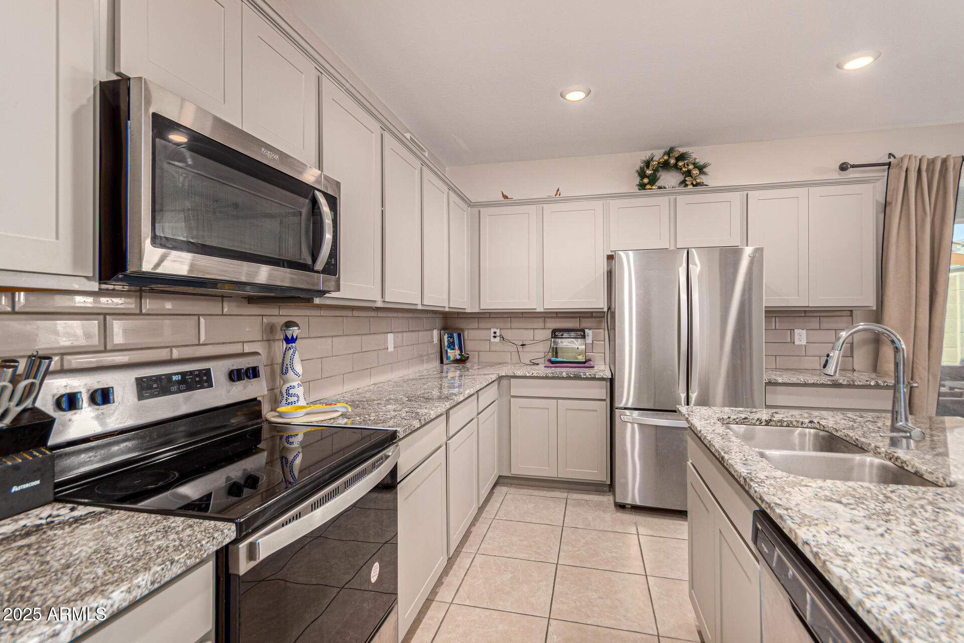 17320 West Daley Lane Surprise, AZ 85387 - Photo 17 of 46 a kitchen with stainless steel appliances granite countertop a sink stove and refrigerator