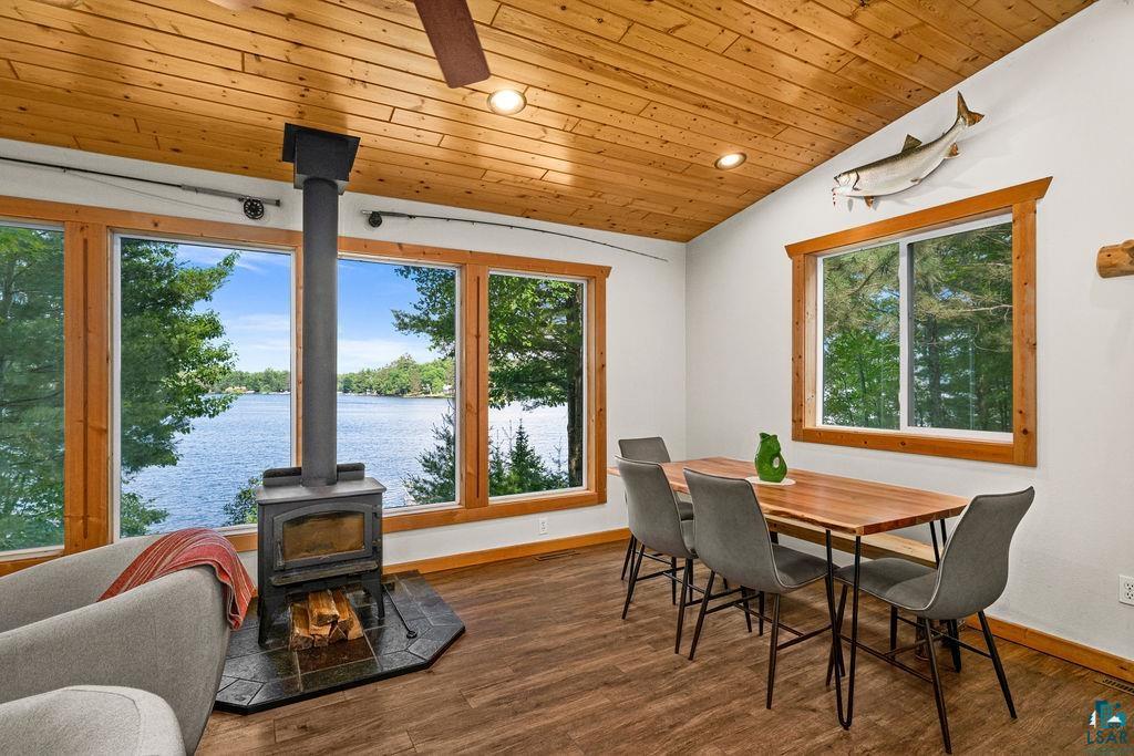 7338 South Maranatha Road Lake Nebagamon, WI 54849 - Photo 23 of 41 Living area featuring a freestanding wood stove with a stone hearth, wood-finish flooring, and a wood plank ceiling