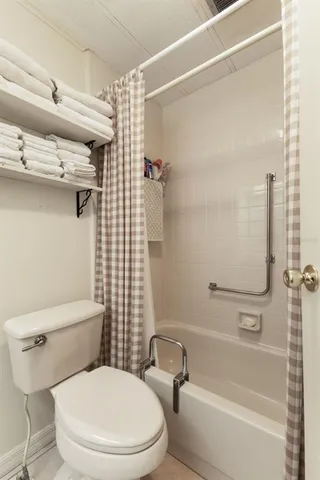 a white toilet sitting next to a bath tub and shower