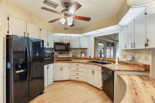 a kitchen with stainless steel appliances granite countertop a refrigerator a stove a sink a stove and white cabinets with wooden floor