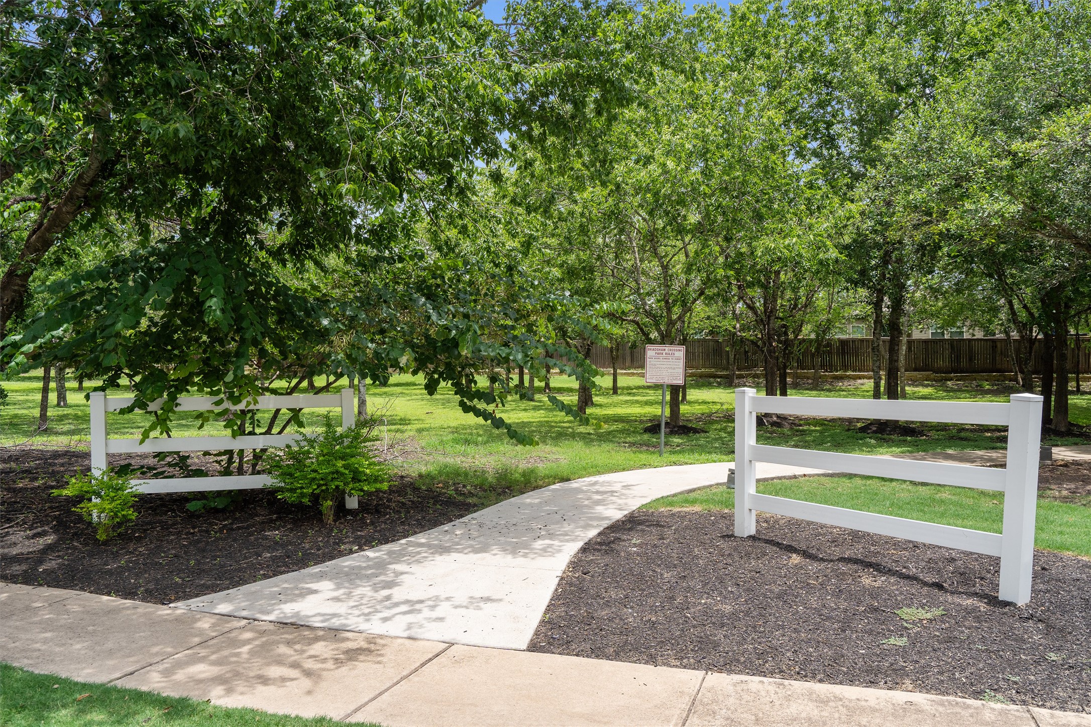 5825 Silver Screen Drive Austin, TX 78747 - Photo 34 of 40 A curved pathway leads into a serene green space, framed by natural wood fencing.