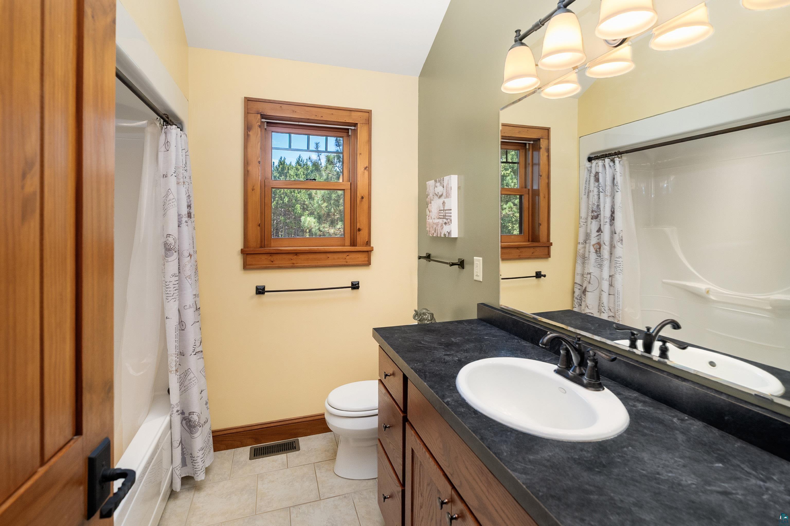 75 East Stark Road Esko, MN 55733 - Photo 34 of 87 Bathroom featuring a dark wood-finish vanity with an integrated sink, black countertop, and a large mirror