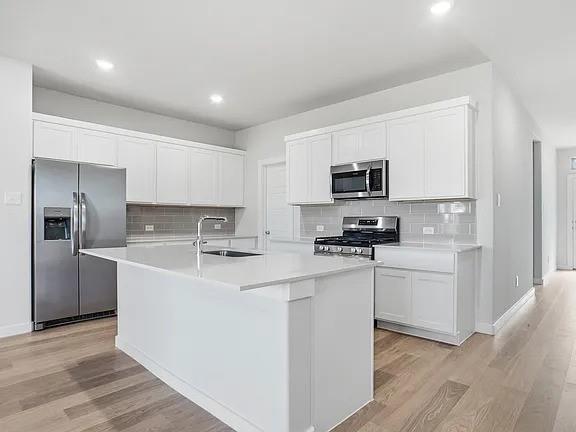 641 Poppy Lane Lavon, TX 75166 - Photo 2 of 12 Kitchen featuring stainless steel appliances, white cabinetry, a kitchen island with sink, light wood-type flooring, and recessed lighting
