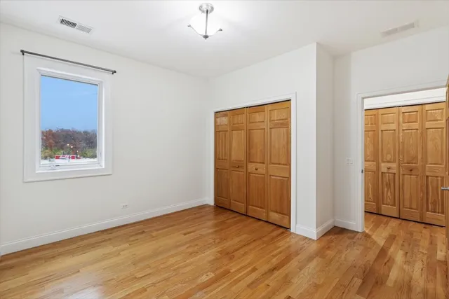 a view of an empty room with wooden floor and a ceiling fan