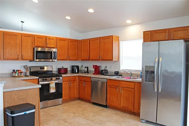 a kitchen with stainless steel appliances granite countertop a refrigerator a sink a stove a microwave and island