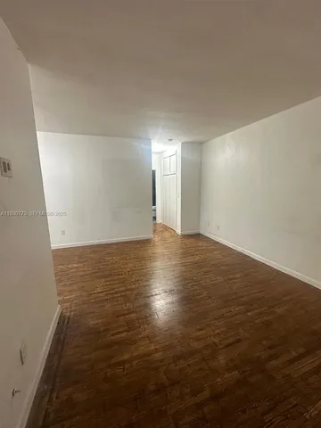 an empty room with wooden floor and windows with curtains