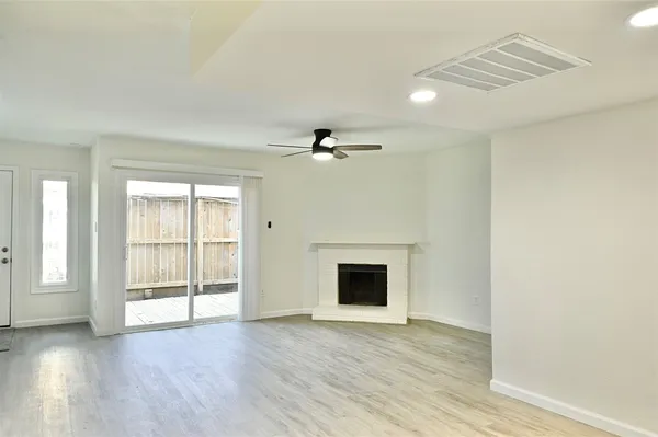 a view of an empty room with wooden floor and a fireplace
