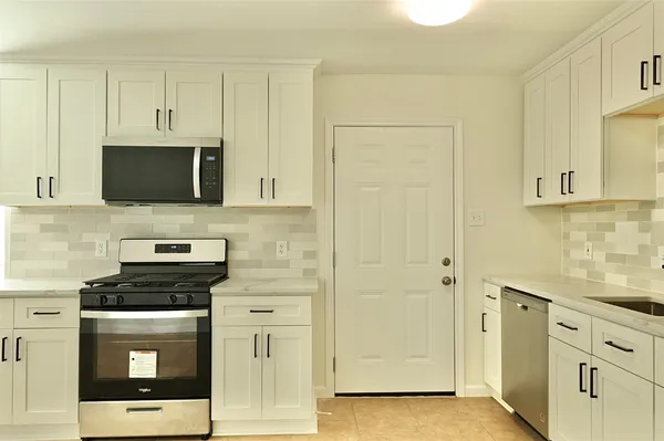a kitchen with stainless steel appliances granite countertop white cabinets and a sink