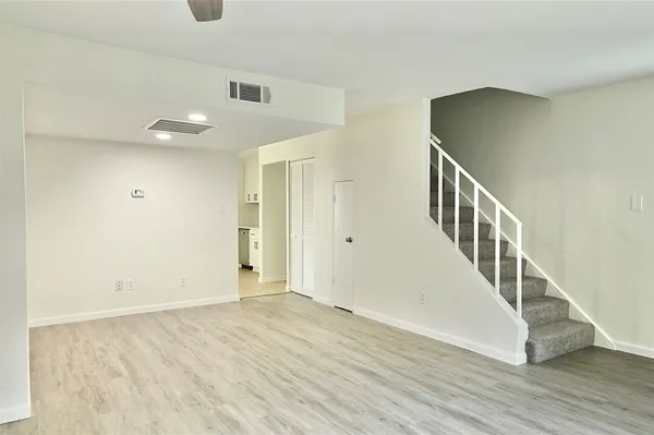 an empty room with wooden floor chandelier fan and windows
