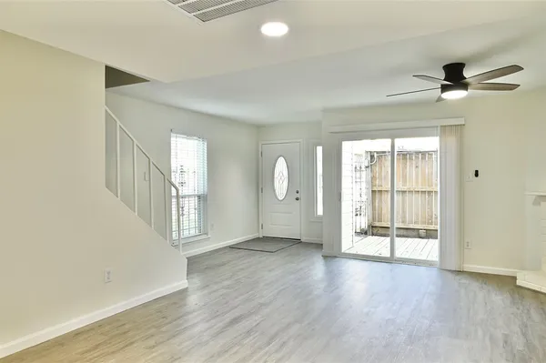 an empty room with wooden floor fireplace and windows