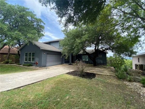 a front view of a house with a yard and trees