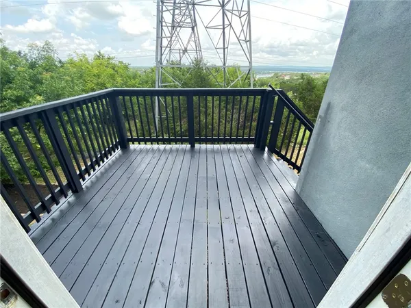 a balcony with wooden floor and trees in the back