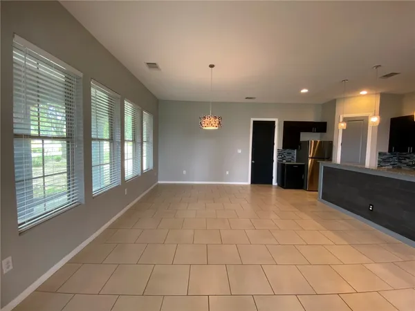 a view of an empty room with kitchen and window