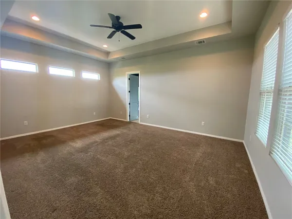 en empty room with windows and ceiling fan