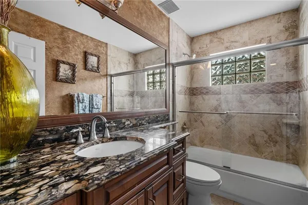 a bathroom with a granite countertop sink toilet and shower