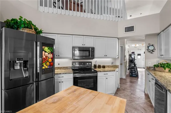 a kitchen with stainless steel appliances kitchen island granite countertop a refrigerator a stove and a sink