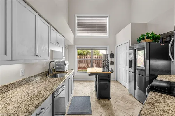 a kitchen with stainless steel appliances granite countertop sink stove refrigerator and cabinets