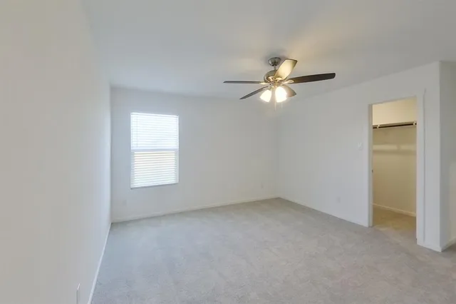 a view of an empty room with a ceiling fan and a window