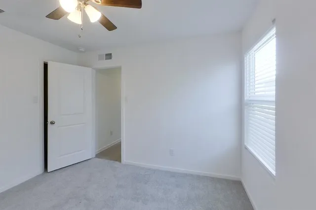 an empty room with a window and a chandelier fan