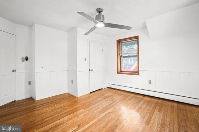 a view of an empty room with a window and wooden floor