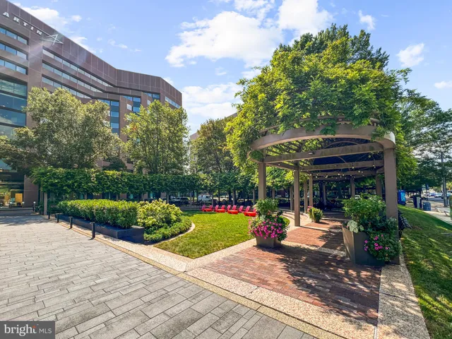 a view of a patio with dining table and chairs under an umbrella with a barbeque