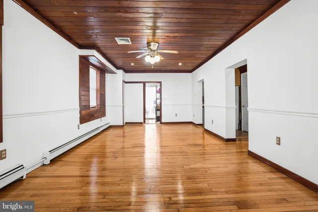 a view of an empty room with window and wooden floor