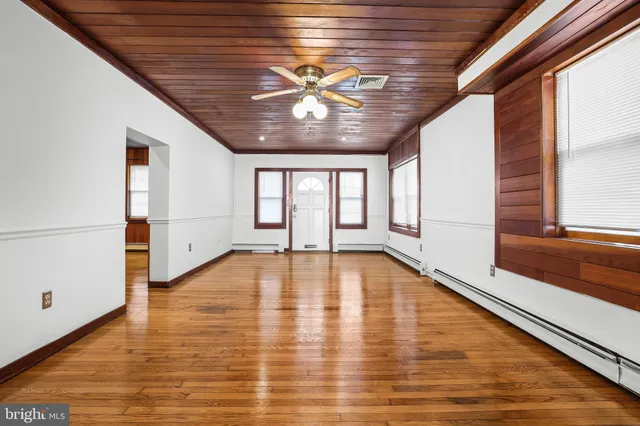 a view of an empty room with a window and wooden floor