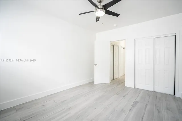 an empty room with wooden floor closet and fan