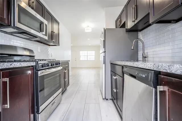 a kitchen with stainless steel appliances granite countertop a sink a stove and a refrigerator