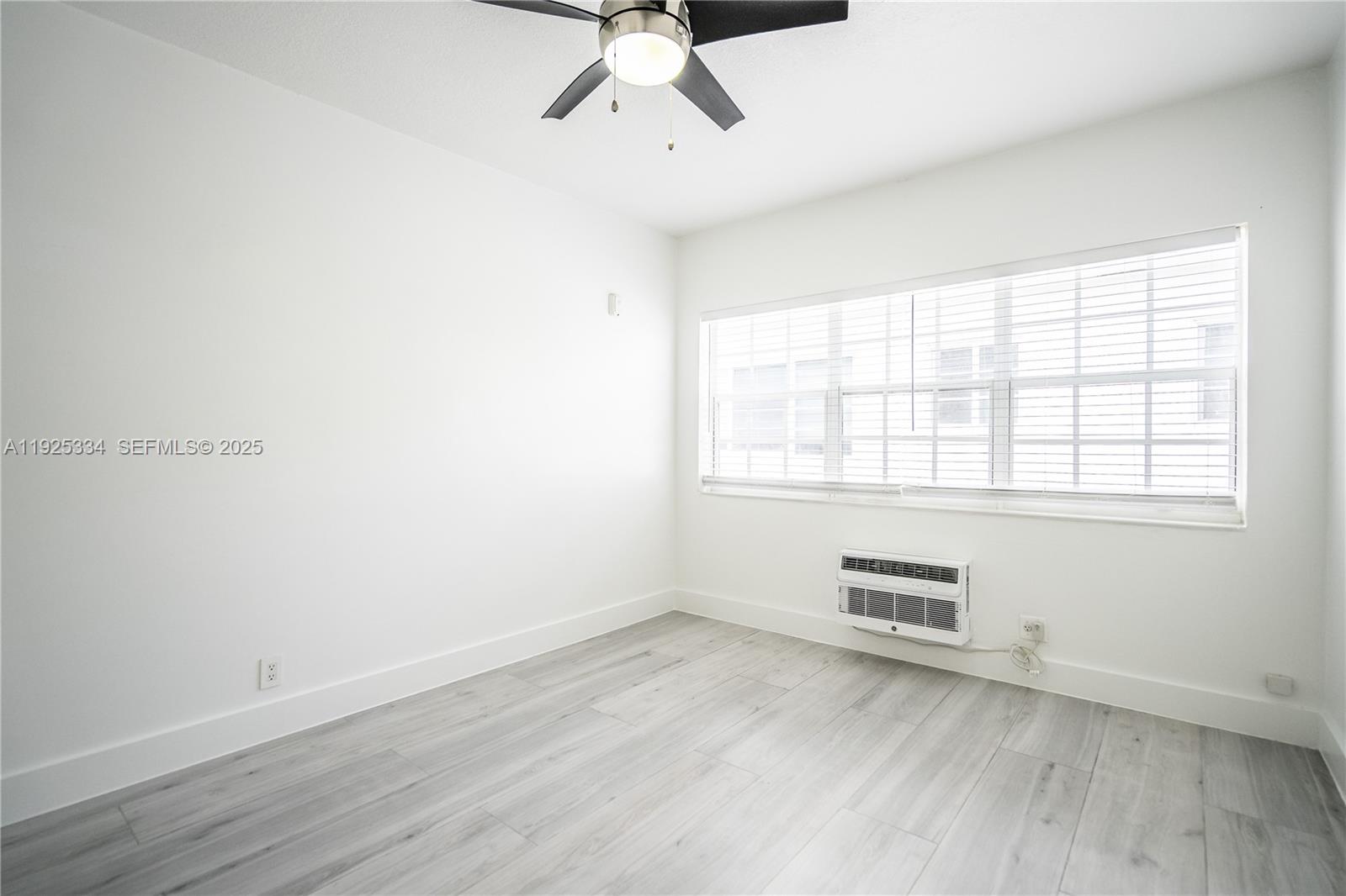 330 84th Street, Unit 9 Miami Beach, FL 33141 - Photo 9 of 16 an empty room with wooden floor and windows
