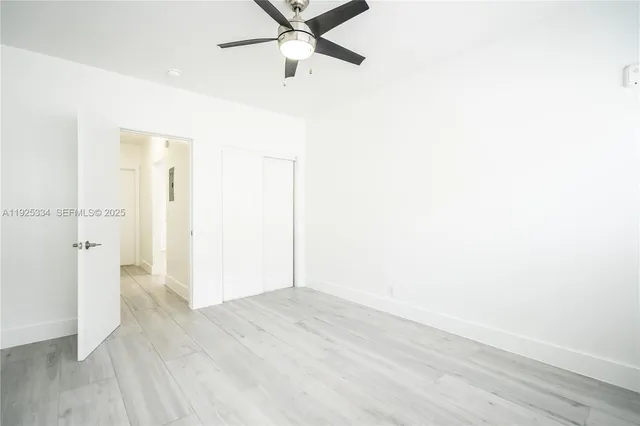 an empty room with wooden floor and a ceiling fan
