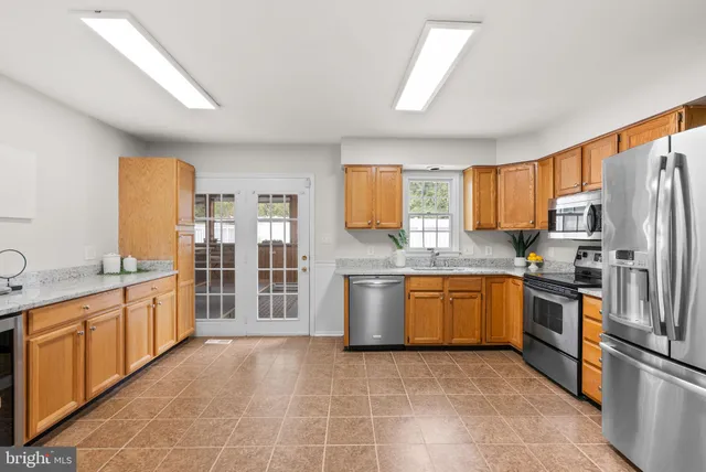 a large kitchen with stainless steel appliances granite countertop a stove a sink dishwasher a refrigerator and a microwave