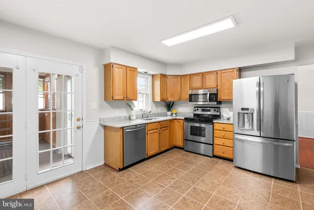 a kitchen with granite countertop stainless steel appliances a refrigerator stove top oven and sink