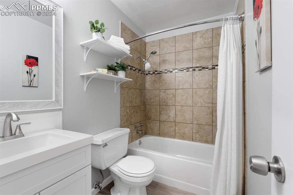 757 Alexander Road, Unit C Colorado Springs, CO 80909 - Photo 12 of 29 Full bathroom featuring wood-type flooring, shower / bath combo with shower curtain, vanity, and toilet