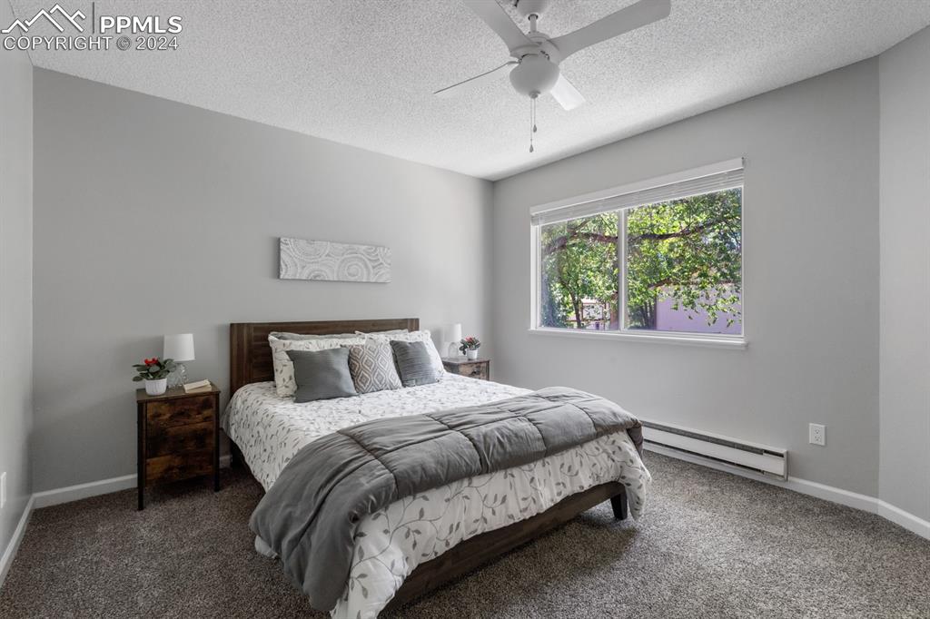 757 Alexander Road, Unit C Colorado Springs, CO 80909 - Photo 15 of 29 Bedroom featuring ceiling fan, dark colored carpet, a textured ceiling, and baseboard heating