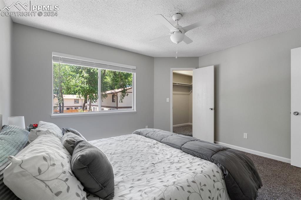 757 Alexander Road, Unit C Colorado Springs, CO 80909 - Photo 17 of 29 Carpeted bedroom with ceiling fan, a closet, a textured ceiling, and a spacious closet