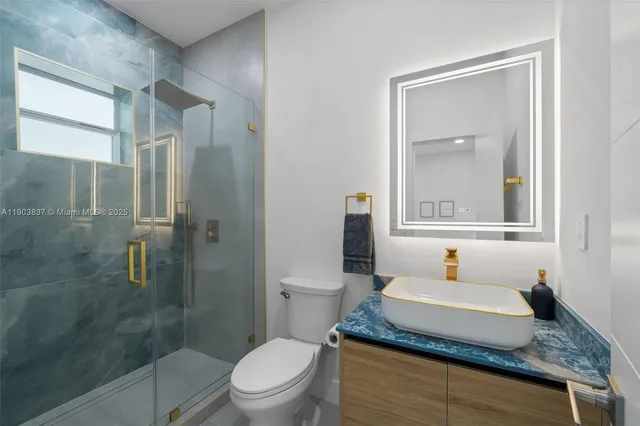 a bathroom with a granite countertop sink toilet a mirror and shower