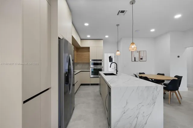 a kitchen with kitchen island a counter top space a sink stainless steel appliances and cabinets