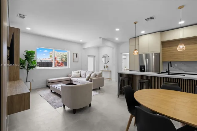 a dining room with kitchen island furniture a chandelier a sink and a refrigerator