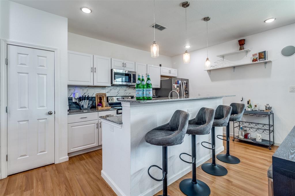 3121 Rutz Street Dallas, TX 75212 - Photo 7 of 24 a kitchen with stainless steel appliances granite countertop a refrigerator a sink a stove and white cabinets with wooden floor