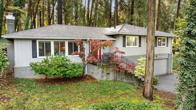 a view of a white house with a yard and table and chairs under an umbrella