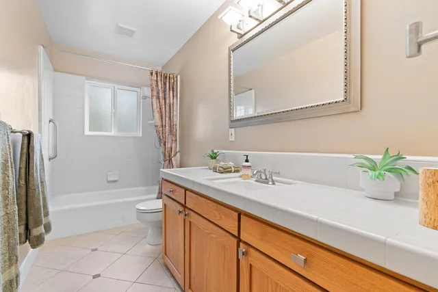 a bathroom with a granite countertop sink a toilet a mirror and shower