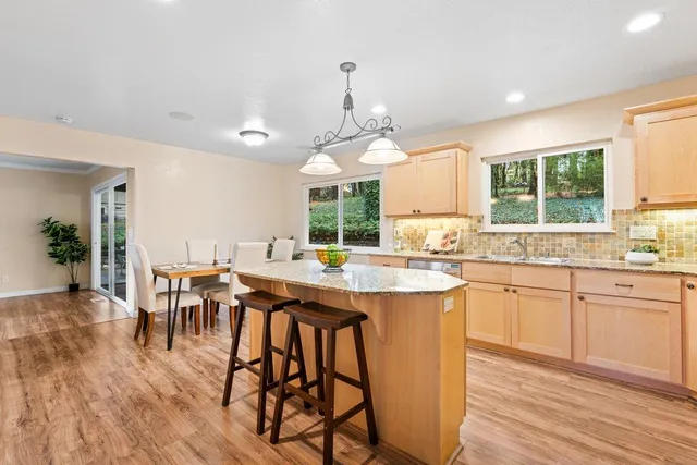 a kitchen with stainless steel appliances granite countertop wooden floor dining table and chairs