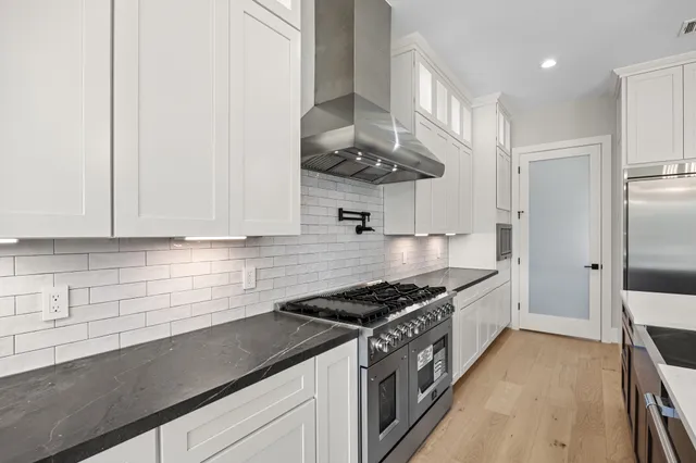 a kitchen with stainless steel appliances granite countertop a sink a stove and a refrigerator