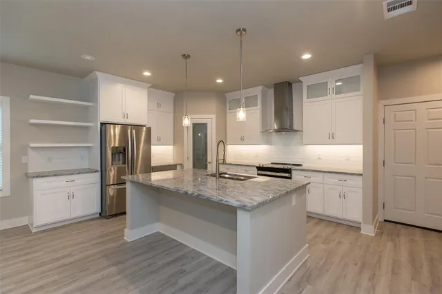a kitchen with a stove a refrigerator and white cabinets with wooden floors
