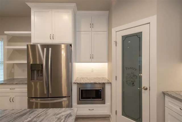 a view of kitchen with granite countertop stainless steel appliances and refrigerator
