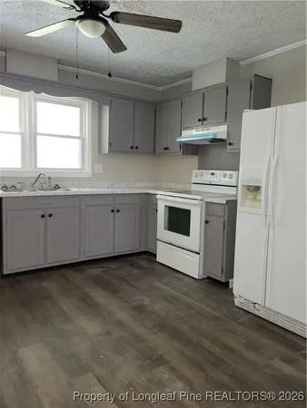 a kitchen with granite countertop white cabinets and white appliances
