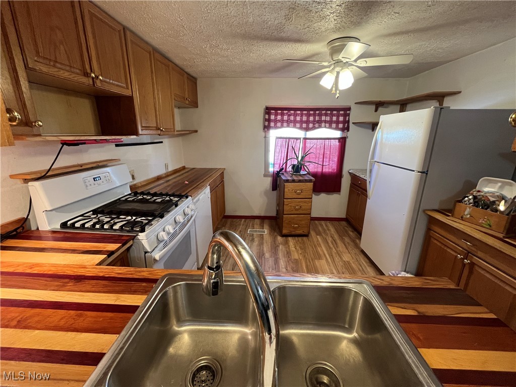 57894 Flamingo Road Senecaville, OH 43780 - Photo 9 of 20 Kitchen featuring brown cabinets, a ceiling fan, a sink, white appliances, and light wood finished floors
